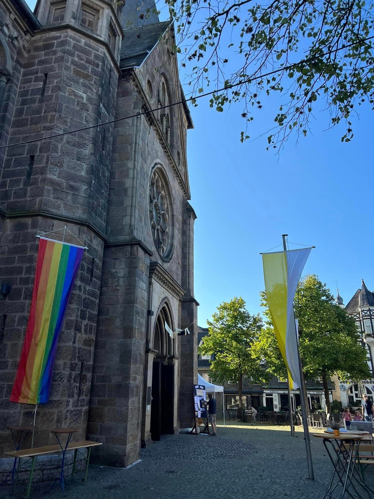Regenbogenflagge Seite an Seite mit den Festflaggen vor der Kirche